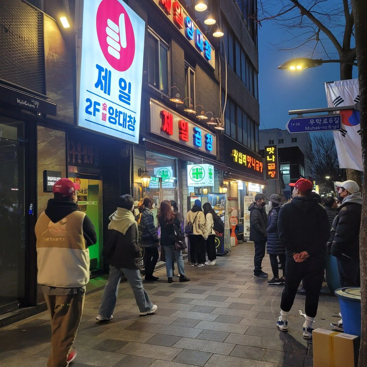 夕方の通りの「제일곱창」の看板と店の前のお客様